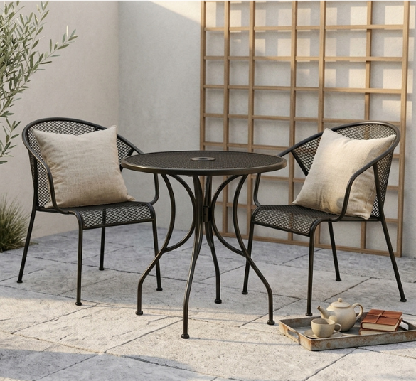 Wide shot of the round table on a sunlit patio, a couple of chairs pulled up, maybe a coffee cup on top to suggest everyday use.