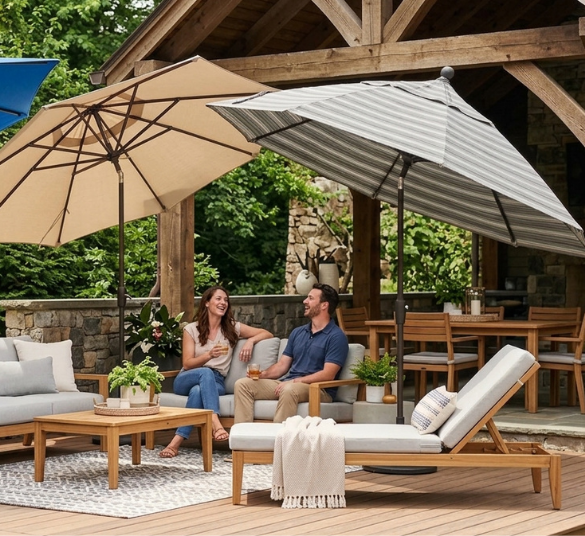 Outdoor Umbrella Fabric Comparison – Polyester, Solution-Dyed, and Sunbrella-Type Canopies Three outdoor umbrellas in blue, tan, and gray-striped fabrics shading a wooden deck with lounge seating, illustrating different canopy materials including polyester, solution-dyed, and Sunbrella-type options.